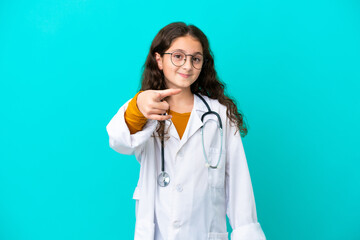 Little doctor girl isolated on blue background surprised and pointing front