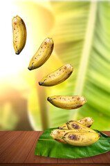 Fresh ripe bananas fall on top of a green banana leaf on the table against the backdrop of a...