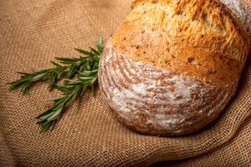 Sourdough bread with Italian herbs and rosemary isolated on burlap cloth.
