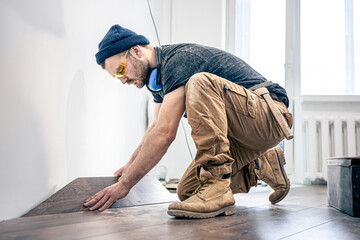 A male worker puts laminate flooring on the floor.