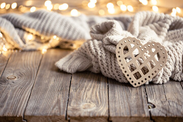 Cozy background with a knitted element, decorative heart and bokeh lights.