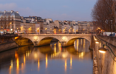 Fototapeta premium Stone bridge Pont au Change in Paris at the dusk. On the left are towers of Conciergerie, on right northern bank of river Seine. Paris.