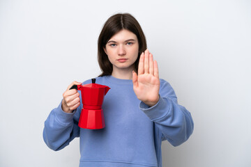 Young Russian woman holding coffee pot isolated on white background making stop gesture