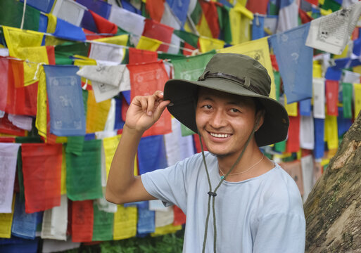 A Asian young guy looking sideways, posing against Buddhist prayer flags