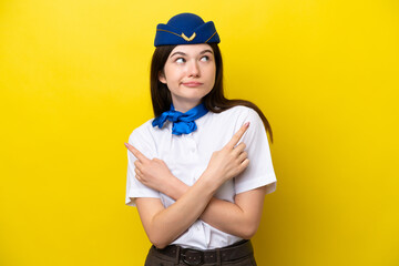 Airplane stewardess Russian woman isolated on yellow background pointing to the laterals having doubts