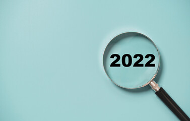 2022 year number insider of magnifier glass on blue background for focus new year business concept.