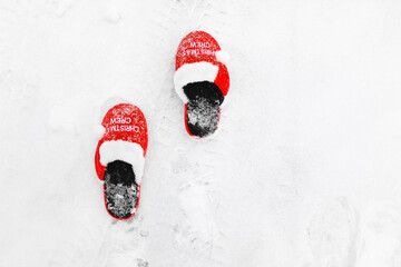 Red home Christmas slippers on the snow in winter.