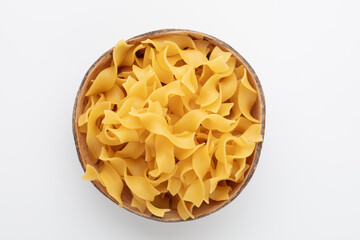 Raw pasta in bowl on old wooden table.