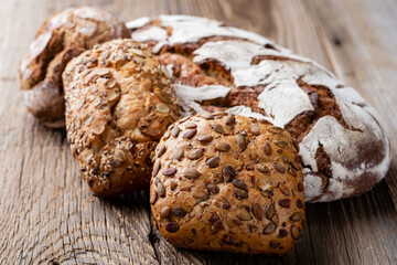 Gold rustic crusty loaves of bread and buns on wooden background. Still life captured from above top view, flat lay.