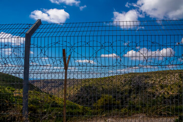 Rows of a barbed wires, fence against blue sky. Concept of freedom