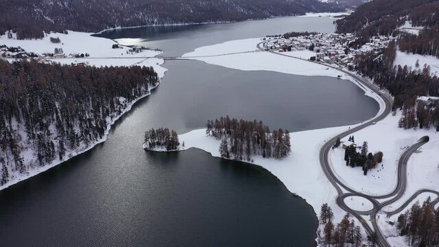Aerial drone footage of the Champfer and Silvaplana lake in the Engadine valley in winter in the alps in Canton Graubunden in Switzerland. Shot with a forward tilt up motion