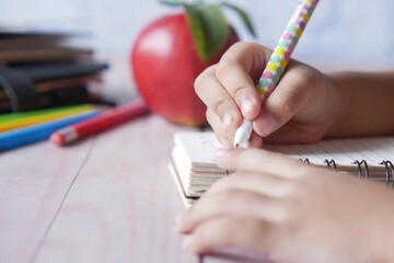 child hand writing on notepad 