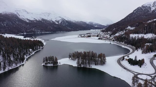 Aerial drone footage of the Champfer and Silvaplana lake in the Engadine valley in winter in the alps in Canton Graubunden in Switzerland. Shot with a upward tilt down motion