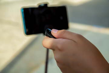 children's hand presses the remote to take a photo on a mobile phone selfie