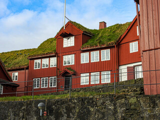 Ein rotes Holzhaus mit bewachsenem Dachauf einer Anh&ouml;he in der Altstadt von Torshavn, Hauptstadt der F&auml;r&ouml;er Inseln 