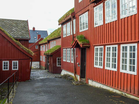 Eine Strasse führt hinab durch die Altstadt von Torshavn, vorbei an mehreren roten Holzhäusern 