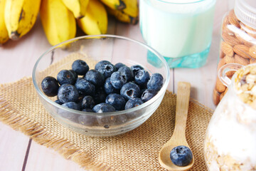  fresh blue berry in bowl with banana, milk and almond on table 