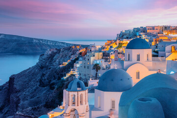 Colorful and Dramatic Sunset with Night Lights in Mediterranean Town of Oia, Santorini, Greece,...