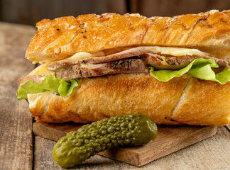 Cubano pork and cheese sandwich in toasted bread. Wooden table.