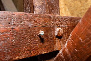 Roof truss visible in the attic house, painted brown with visible cracks in the wood, walls covered...