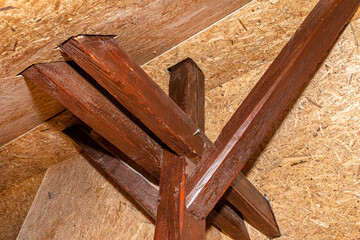 Roof truss visible in the attic house, painted brown with visible cracks in the wood, walls covered...