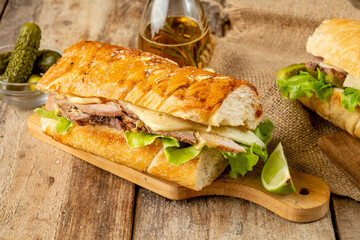 Traditional cuban sandwich with cheese, ham and fried pork, served on a wooden board
