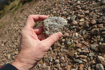 white granite stone with gray splashes in a human hand close-up