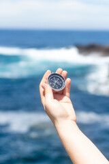 Close up, Hand holding a compass in front of the ocean. Travel, concepts