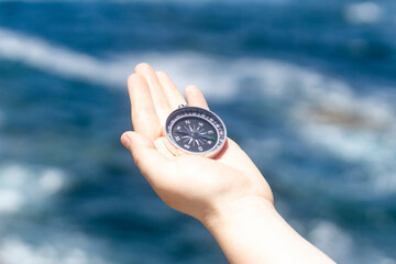 Close up, Hand holding a compass in front of the ocean. Travel, concepts