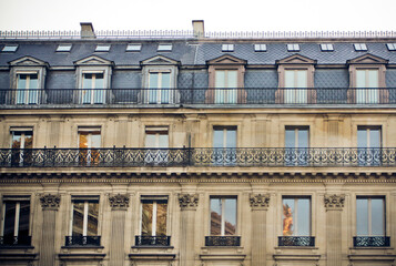  Facade of a traditional parisian living building with large windows and balconies with fort-iron grillein - obrazy, fototapety, plakaty