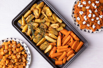 Baked parsnip, carrot and sweet potato. Roasted root vegetable top view on white table.