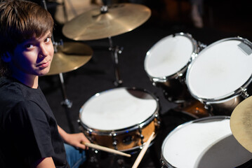 Fototapeta na wymiar A boy plays drums in a recording studio