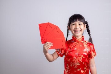 Happy Little Asian girl in Chinese traditional dress smiling and holding a red envelope. Happy Chinese new year concept.