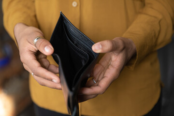 Close up young African American unemployed woman holding opened empty black leather wallet. feeling...