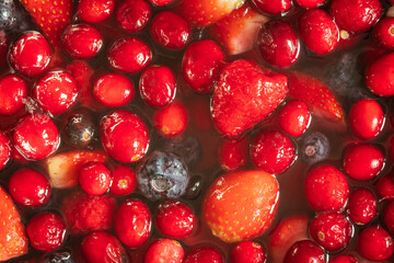 frozen mix strawberries blueberries raspberries and cranberries in water closeup