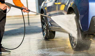 Closeup of male driver washing his car with contactless high pressure water jet in self service car...