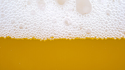 MACRO: Tiny bubbles form the foam on top of a glass full of pale ale beer.