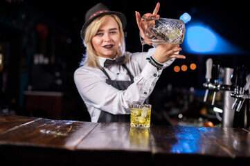 Girl barman concocts a cocktail behind the bar