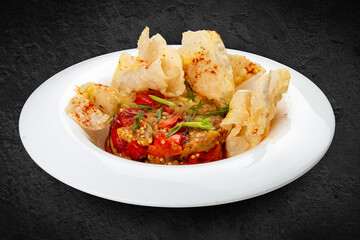 Warm vegetable salad on the grill. Eggplant, tomatoes and sweet pepper. Isolated on a black background.