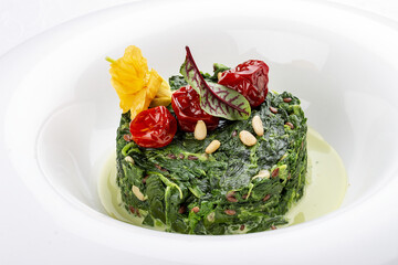 Stewed spinach with pine nuts. Isolated on a white background.