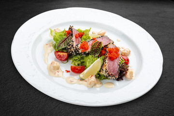 Tuna on a pillow of chuka with shrimp sauce . Isolated on a black background.