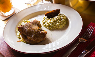 dish duck leg with green perlotto served on a white plate