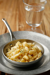 Creamy Macaroni and Cheese on a Skillet Oan with Parmesan and Herbs, Isolated on Wooden Table