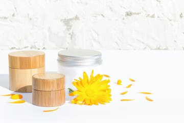 Set of cosmetics. Natural cosmetic. Bamboo jars, glass jar with cream. Calendula. Light background.