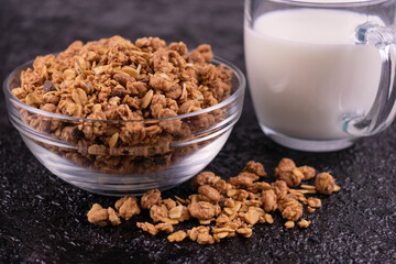 Homemade granola and milk on a black background.
Close-up.