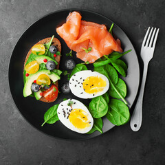 Delicious breakfast, tapas, appetizer. Bread, vegetables, herbs, spinach, eggs, salmon, berries, blueberries. Top view