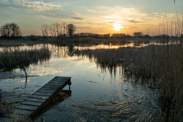 A small footbridge on the shore of a lake and sunset