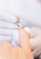 Obraz na płótnie Canvas manicurist with white gloves uses a cuticle tool. beauty treatments, manicure