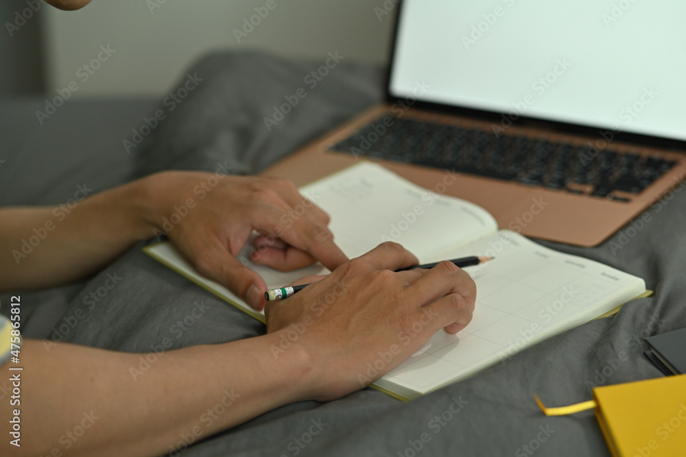 Poster cropped image of a university student doing homework with a white blank screen computer laptop on th