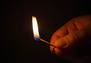 Lit matchstick in dark room. Blackout city or power outage concept.